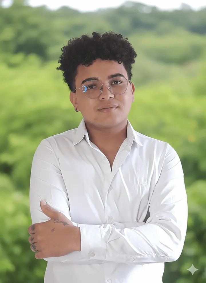 Alexi Durán Gómez, con camisa blanca y gafas, de brazos cruzados frente a un fondo verde.